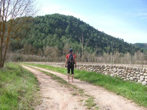 a man walking down a dirt road with a backpack at La Farga de la Muga in Sant Llorenç de la Muga