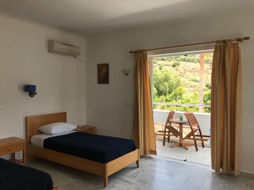 a bedroom with a bed and a balcony with a table at Kanakis Blue Beach Apartments in Petres