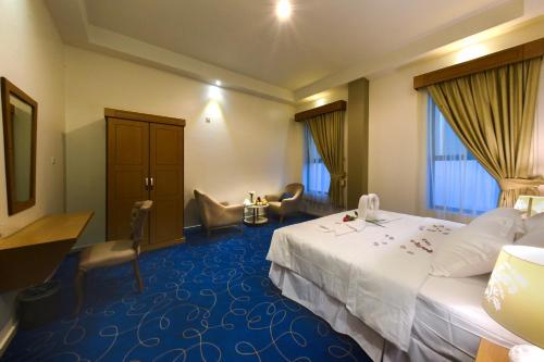 a hotel room with a large bed and a chair at Fiori Hotel Suites in Al Ahsa