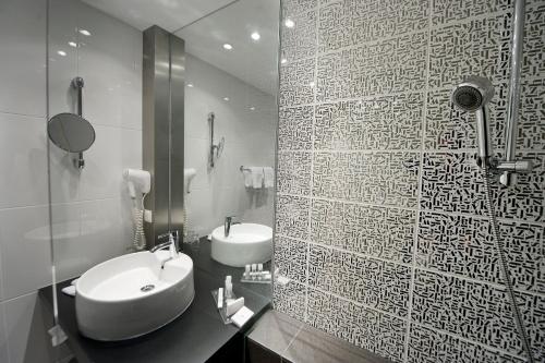 La salle de bains est pourvue d'un lavabo blanc et d'un miroir. dans l'établissement Pannonia Tower, à Parndorf
