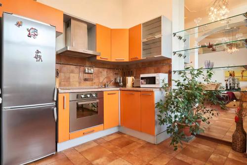 a kitchen with orange cabinets and a stainless steel refrigerator at Home Hotel Apartments on Kontraktova Ploshcha in Kyiv