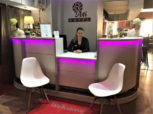 une femme assise au comptoir avec des chaises roses dans l'établissement A1 Hotel Riga City Center, à Riga