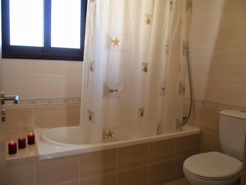 a bathroom with a toilet and a tub with stars on the shower curtain at Kyklades Resort & Spa in Paralimni