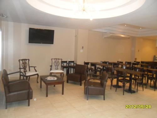a dining room with tables and chairs and a tv at Destino Real Hotel in Buenos Aires