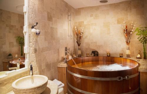 a bathroom with a wooden tub and a sink at Domaine du Haut Jardin Hôtel & Chalets Spa Privé in Rehaupal
