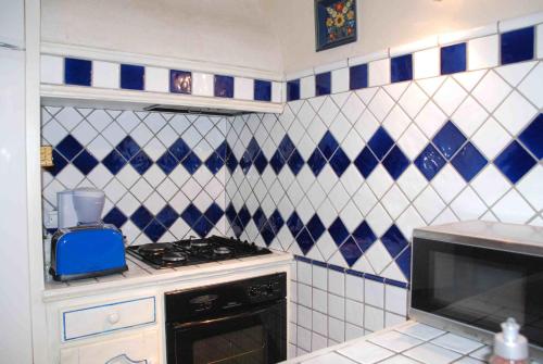 SernhacにあるLa Petite Maison De Velinaの青と白のタイル張りの壁、キッチン(コンロ付)