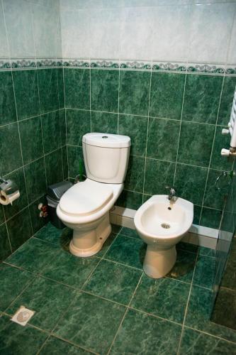 a green tiled bathroom with a toilet and a bidet at Boutique Hotel Eco-House Tbilisi in Tbilisi City
