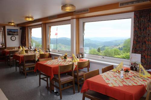 a restaurant with tables and chairs and large windows at Hotel Hulfteggpass in Mühlrüti