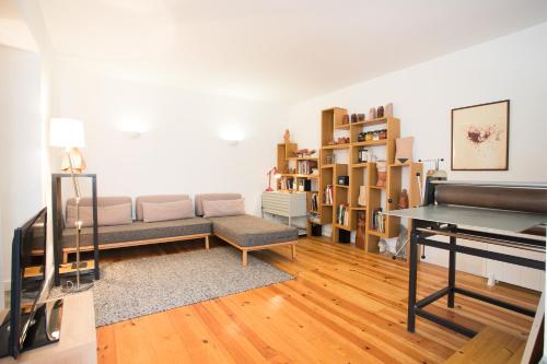 uma sala de estar com um sofá e pisos em madeira em FLH Castelo Cozy Flat em Lisboa