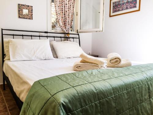 Una cama con una manta verde y toallas. en Phoenix cosy home ΙΙ, en Livadakia