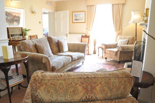 a living room with a couch and chairs and a tv at Tyddyn Llan Restaurant with Rooms in Corwen
