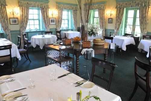 a restaurant with white tables and chairs and windows at Tyddyn Llan Restaurant with Rooms in Corwen
