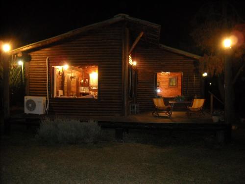 a log cabin at night with lights on the porch at Cabañas Las Lavandas en Pilar in Pilar