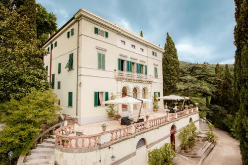 a large white house with a large white balcony at Villa Alta - Residenza d'epoca con piscina in San Giuliano Terme