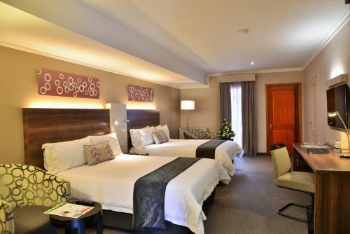 a hotel room with two beds and a desk at Birchwood Hotel and OR Tambo Conference Centre in Boksburg