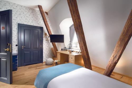 a bedroom with a bed and a desk and a door at Relais & Châteaux Hotel Quadrille - Adults Only in Gdynia