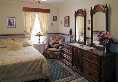 a bedroom with a bed and a dresser and a chair at The Spanish Guesthouse, pets considered in Perth