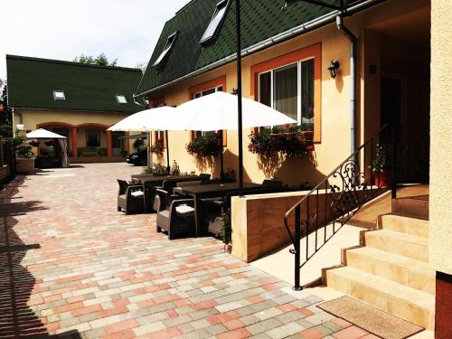 a patio with tables and umbrellas next to a building at Pensiunea Lucia in Sfântu-Gheorghe