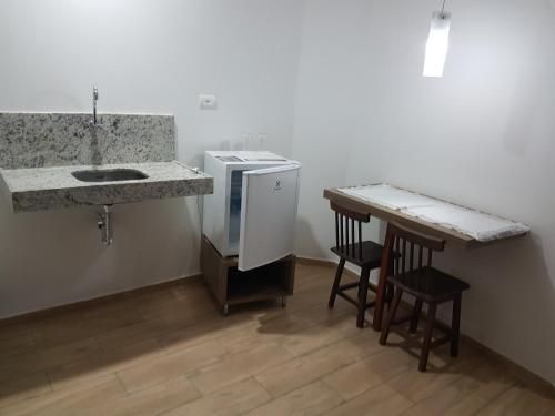 uma cozinha com um balcão e um lavatório e dois bancos em Hotel Reobot Center em Garanhuns