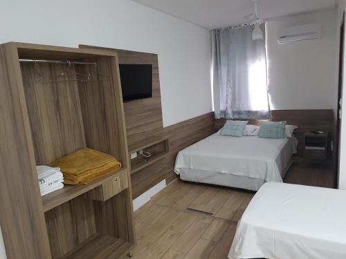 um pequeno quarto com 2 camas e uma televisão em Hotel Reobot Center em Garanhuns