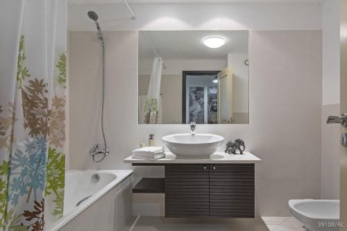 Un baño con lavabo, bañera y espejo. en Rodamar I by An Island Apart, en Funchal