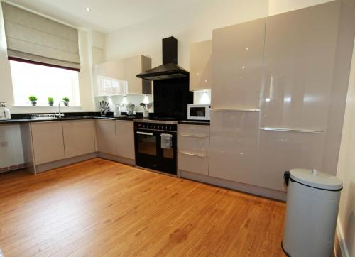 a kitchen with white cabinets and a wooden floor at Hunter House Apartment FREE PARKING ONSITE in York