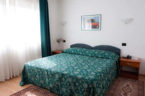 a bedroom with a bed with a green comforter at Hotel Makin in Novigrad Istria