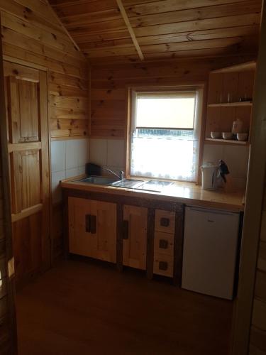 a kitchen in a log cabin with a sink and a window at Domki Letniskowe Poranek in Jezierzany
