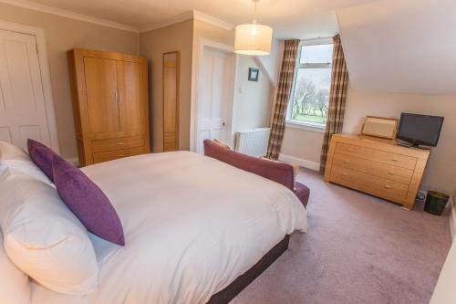 a bedroom with a large bed and a television at Butt Lodge in Lochranza