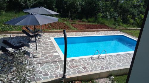 an umbrella and chairs next to a swimming pool at Apartment Adriatic in Umag
