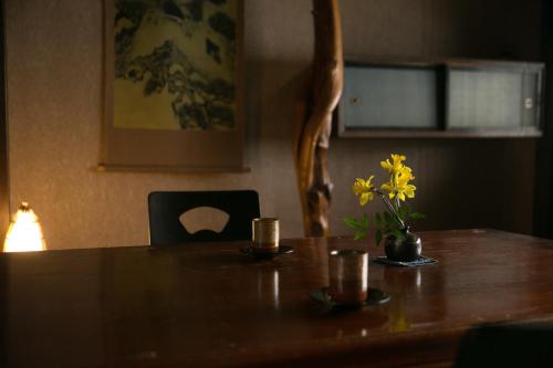 a wooden table with a vase of yellow flowers on it at Isamikan in Nakagawa