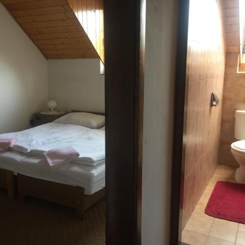a small bedroom with a bed and a bathroom at Ilona Panzió in Balatonlelle