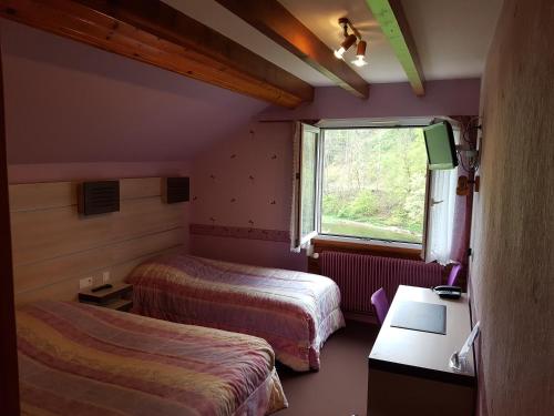 a hotel room with two beds and a window at Auberge Le Moulin Du Plain in Goumois
