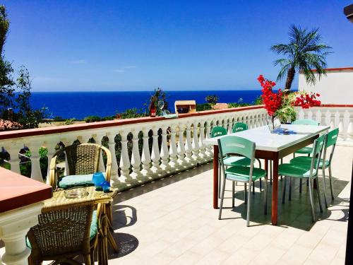 a table and chairs on a balcony with the ocean at Mazzitelli Apartment in Capo Vaticano