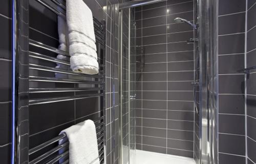 baño con paredes de azulejos negros y ducha. en The Kings Apartment en York