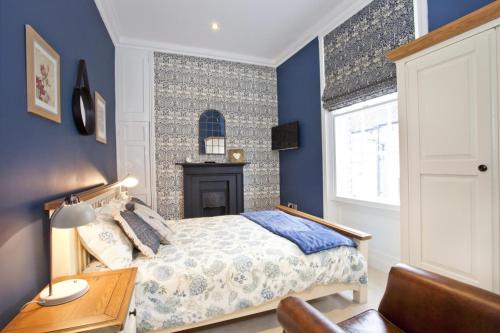 1 dormitorio con paredes azules, 1 cama y escritorio en The Kings Apartment en York