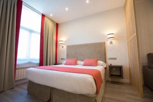 a bedroom with a large bed with two red pillows at Hotel Santa Cruz in Cangas de Onís