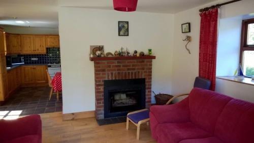a living room with a fireplace and a red couch at The Old Coastguard Station in Cahersiveen