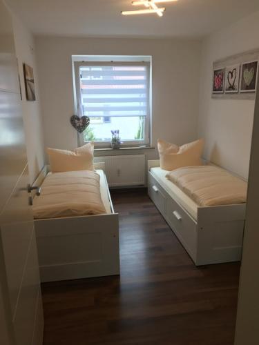 two beds in a room with a window at Ermmes Ferienwohnungen in Sinsheim
