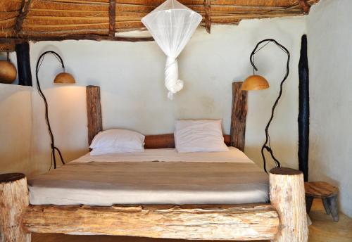 ein Schlafzimmer mit einem Holzbett mit zwei Lampen in der Unterkunft Tama Lodge in M'bour