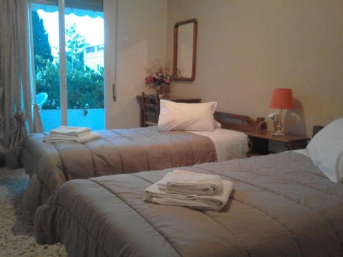 a hotel room with two beds and a window at Captain's Rooms in Aegina Town