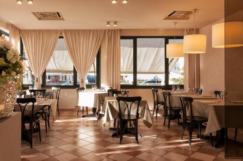 un restaurante con mesas, sillas y ventanas grandes en Hotel Villa Toscana, en Lido di Camaiore