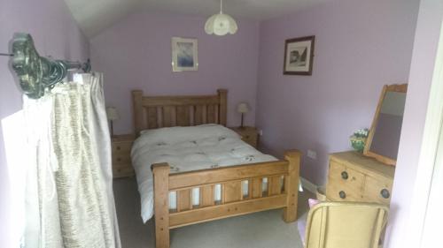 a bedroom with a bed and a dresser and a television at Fern Farm Cottages in Buxton