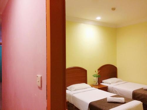 納閩的住宿－斯凱戈婁博酒店，黄色墙壁客房的两张床