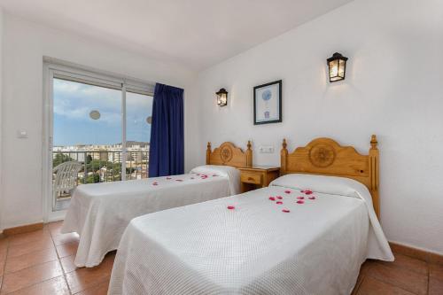 a room with two beds with roses on them at Apartamentos Embajador in Fuengirola