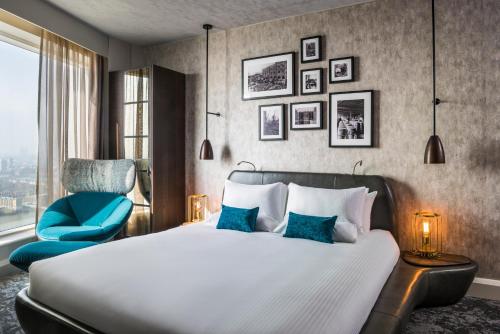 a bedroom with a bed and a blue chair at Novotel London Canary Wharf in London