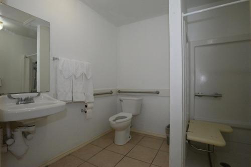 a white bathroom with a toilet and a sink at Port Isla Inn in Port Isabel