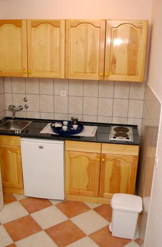 a kitchen with wooden cabinets and a sink and a toilet at Apartments Adria in Orebić