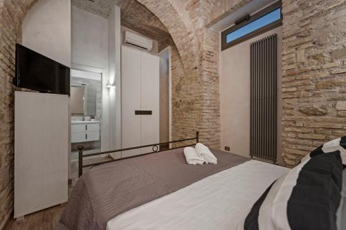 ローマにあるWhite flat Rione Montiのレンガの壁、ベッド1台、テレビが備わるベッドルーム1室が備わります。