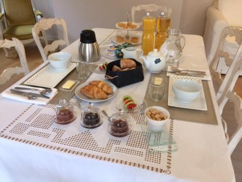 a table with breakfast foods and drinks on it at La Maison Des Buis in Falaise